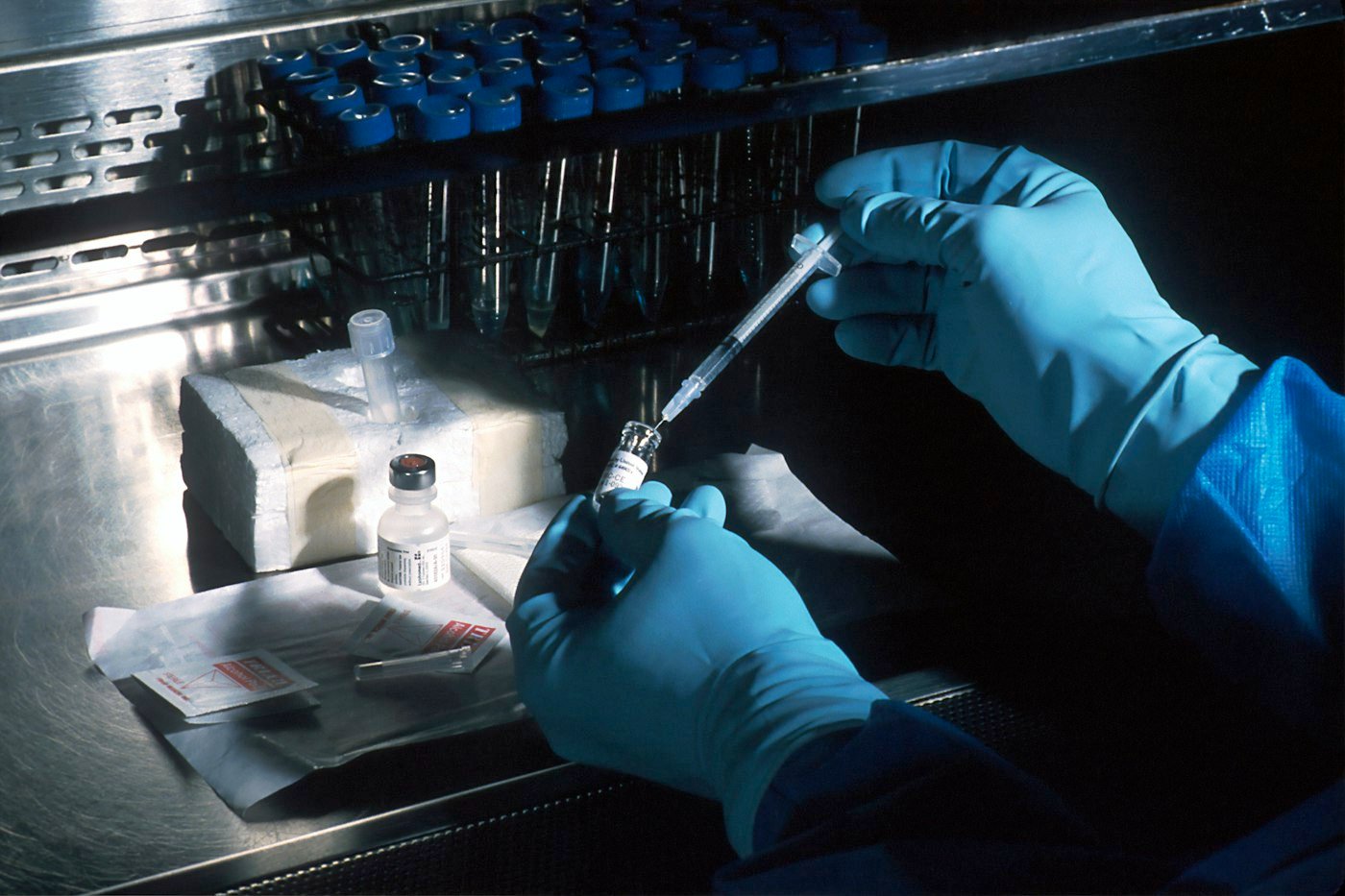 Mains gantées prélevant un vaccin dans un flacon